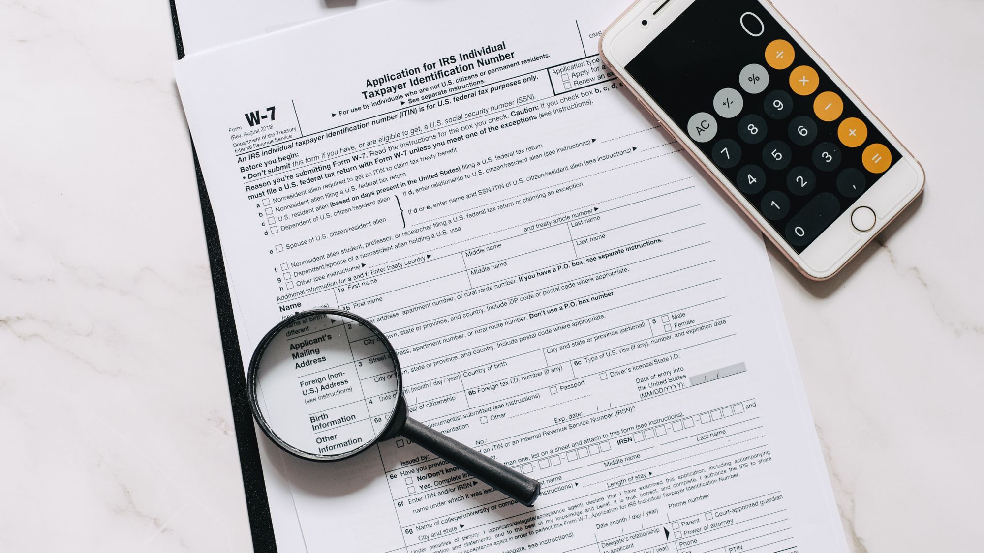 A magnifying glass and calculator resting on printed documents